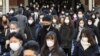 People wear face masks as they leave a train station in Tokyo, Jan. 20, 2023.