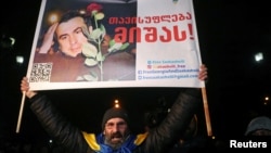 A supporter of Georgia's jailed ex-President Mikheil Saakashvili holds a banner reading "Freedom to Misha!" during a rally outside a court building in Tbilisi, Georgia Feb. 6, 2023.