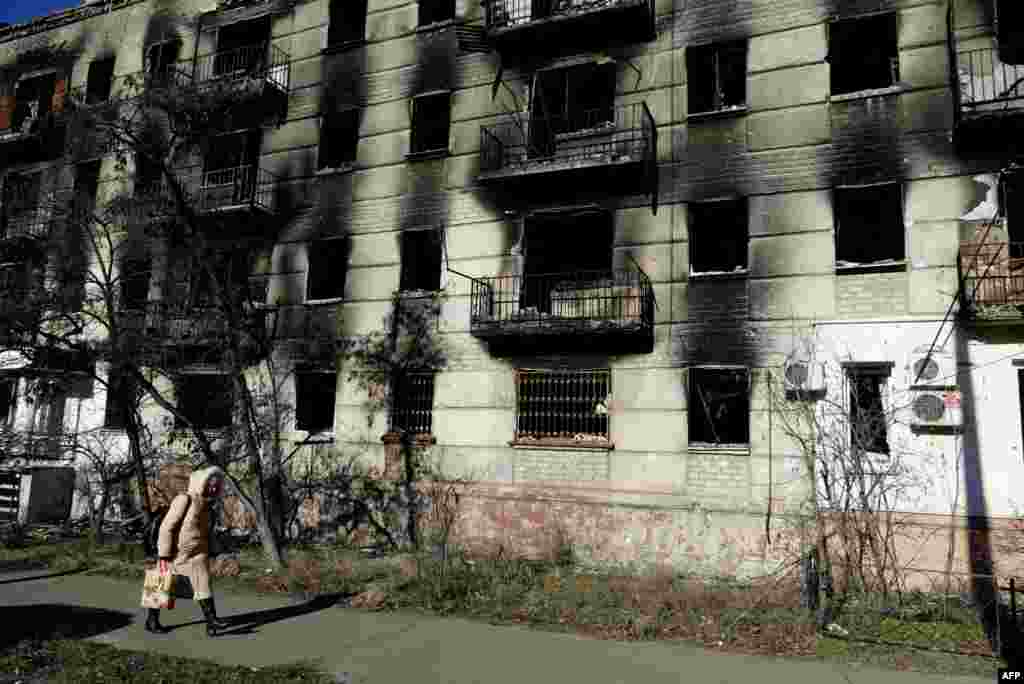 Една жена поминува покрај уништен станбен блок во Украина, во источниот регион Луганск.