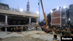 Rescue workers use a crane to lift a portion of a collapsed roof after a suicide blast in a mosque in Peshawar, Pakistan, Jan. 30, 2023.