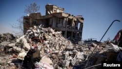A man sits among rubble in the aftermath of a deadly earthquake in Kahramanmaras, Turkey, Feb. 11, 2023. 