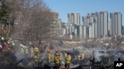 Petugas pemadam kebakaran dan petugas penyelamat membersihkan lokasi kebakaran di desa Guryong di Seoul, Korea Selatan, Jumat, 20 Januari 2023. (AP/Ahn Young-joon)