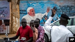 Petugas polisi lalu lintas berdiri di depan mural Paus Fransiskus di dinding gereja di Juba, Sudan Selatan, 2 Februari 2023. (Foto: AP)