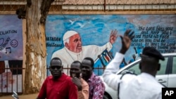 Un oficial de la policía de tránsito parado frente a un mural del Papa Francisco en la pared de una iglesia dirige los vehículos en Juba, Sudán del Sur, el 2 de febrero de 2023.