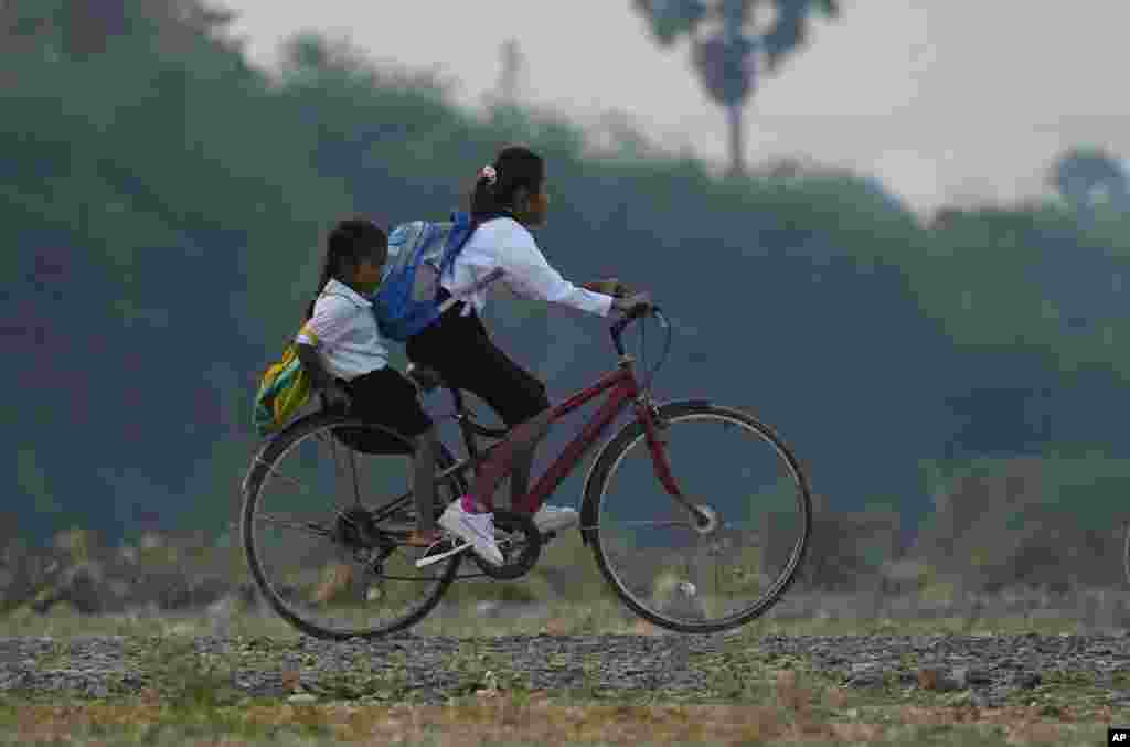 School children ride a bicycle to school on the outskirts of Phnom Penh, Cambodia.
