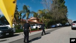 Police block the street to a house where three people were killed and four others wounded in a shooting at a short-term rental home in an upscale Los Angeles, California, neighborhood on Jan. 28, 2023.