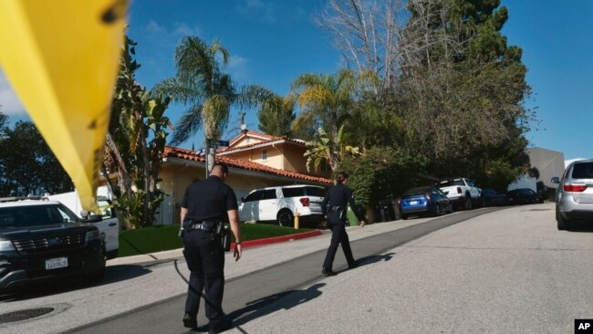Police block the street to a house where three people were killed and four others wounded in a shooing at a short-term rental home in an upscale Los Angeles neighborhood on Jan. 28, 2023.