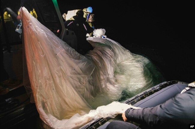 This image provided by the U.S. Navy shows sailors assigned to Explosive Ordnance Disposal Group 2 recovering a high-altitude surveillance balloon off the coast of Myrtle Beach, S.C., Feb. 5, 2023. (U.S. Navy via AP)