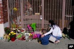 A woman comforts her son while visiting a makeshift memorial outside Star Dance Studio in Monterey Park, Calif., Jan. 23, 2023. (AP Photo/Jae C. Hong)