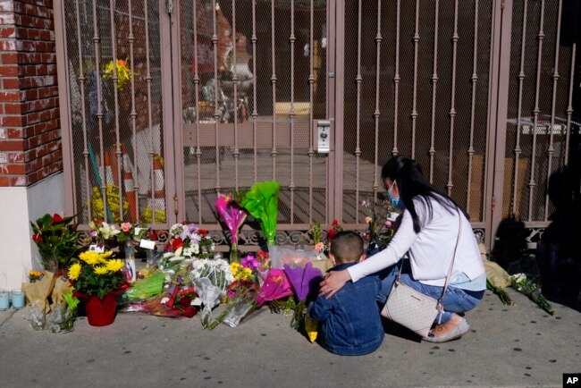 A woman comforts her son while visiting a makeshift memorial outside Star Dance Studio in Monterey Park, Calif., Jan. 23, 2023. (AP Photo/Jae C. Hong)