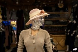 Shop owners use everything from tailored cloth to tin foil to mask their mannequins, hoping to still keep their windows attractive to draw customers in at a time of economic collapse.