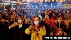 Para jemaah memberikan persembahan pertama mereka di dalam Kuil Wong Tai Sin, sesaat sebelum Tahun Baru Imlek, di tengah pandemi COVID-19 di Hong Kong, China, 21 Januari 2023. (Foto: REUTERS/Tyrone Siu)