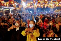 Para jemaah yang mengenakan masker memberikan persembahan pertama mereka di dalam Kuil Wong Tai Sin, sesaat sebelum Tahun Baru Imlek, di tengah pandemi COVID-19 di Hong Kong, China, 21 Januari 2023. (Foto: REUTERS/Tyrone Siu)