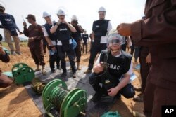 Seorang penjinak ranjau Ukraina (kedua dari kanan), mendengarkan staf Pusat Aksi Ranjau Kamboja, CMAC, di dekat ranjau yang telah dijinakkan di ladang ranjau, desa Preytotoeung, provinsi Battambang, Kamboja, Kamis, 19 Januari 2023. (AP/Heng Sinith)