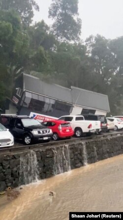 This still image from a social media video shows a collapsed building after a flood in French Bay, Titirangi, New Zealand, Jan. 27, 2023. (Courtesy of Shaan Johari via Reuters)