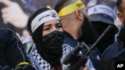 FILE- A masked Palestinian woman holds a gun as Palestinian gunmen gather in solidarity with Palestinians that where killed in clashes with Israeli troops, Feb. 10, 2023.
