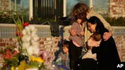 A family gathers at a memorial outside the Star Ballroom Dance Studio, Jan. 24, 2023, in Monterey Park, California.