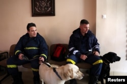 Members of the Disaster Response Special Unit with their dogs wait to board the Hellenic Air Force C-130, in order to fly to Turkey to help in the aftermath of an earthquake, before departing from the military airport of Elefsina, Greece, Feb. 6, 2023.