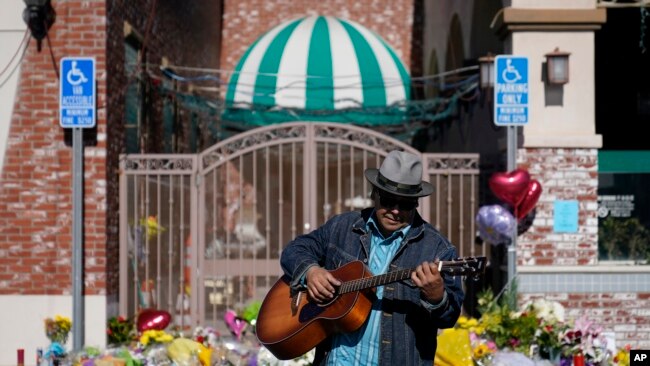 Gabriel Alexander toca una guitarra y canta cerca de un monumento fuera del Star Ballroom Dance Studio el martes, 24 de enero de 2023, en Monterey Park, California.