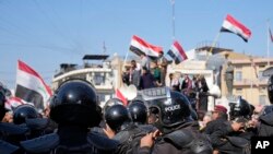 Pasukan keamanan menjaga aksi demontrasi di depan Bank Sentral Irak di Baghdad, pada 25 Januari 2023, di mana massa mengecam nilai tukar mata uang Irak yang melemah terhadap dolar AS. (Foto: AP/Hadi Mizban)