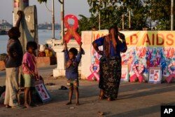 FILE - Street children play with red ribbon left on display by activists on the banks of the Hooghly River ahead of World AIDS Day in Kolkata, India, Nov. 30, 2022.