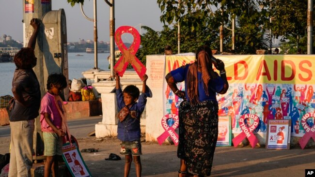 Street children play with red ribbon left on display by activists on the banks of the Hooghly River ahead of World AIDS Day in Kolkata, India, Nov. 30, 2022.