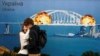 Пара на фоні зображення збудованого Росією Кримського мосту у вогні, Київ, Україна, 8 жовтня 2022 року. Фото: REUTERS/Vladyslav Musiienko/File Photo