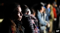 FILE - A woman from Cuba waits with other migrants to be processed to seek asylum after crossing the border into the United States, Jan. 6, 2023, near Yuma, Arizona.