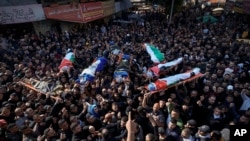 2023年1月26日，在约旦河西岸城市杰宁举行的联合葬礼上，哀悼者抬着八名巴勒斯坦人的尸体，其中一些人披着伊斯兰圣战组织的旗帜。（美联社照片）