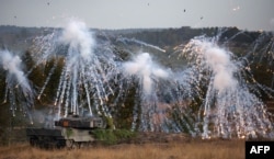 FILE - A Leopard 2 main battle tank throws fog grenades during a visit by the German Chancellor of the German armed forces Bundeswehr troops during a training exercise at the military ground in Ostenholz, northern Germany, on Oct. 17, 2022.