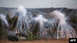 FILE - A Leopard 2 main battle tank throws fog grenades during a visit by the German Chancellor of the German armed forces Bundeswehr troops during a training exercise at the military ground in Ostenholz, northern Germany, on Oct. 17, 2022.