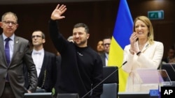 Ukraine's President Volodymyr Zelenskyy, center, gestures as European Parliament's President Roberta Metsola, right, applauds during an EU summit at the European Parliament in Brussels, Belgium, Feb. 9, 2023.