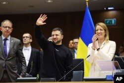 Ukraine's President Volodymyr Zelenskyy, center, gestures as European Parliament's President Roberta Metsola, right, applauds during an EU summit at the European Parliament in Brussels, Belgium, Feb. 9, 2023.