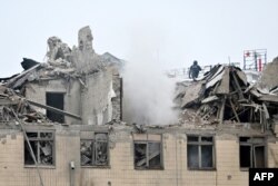 This photo taken on Feb. 5, 2023 shows a rescuer on the top of the partially destroyed building of the National University of Urban Economy after a Russian missile strike in Kharkiv.