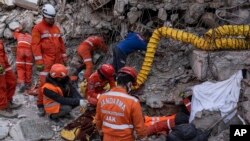 Rescue workers of the Search and rescue unit of the Turkish Gendarmerie General Command work to pull 23-year-old Huseyin Seferoglou from the rubble of a collapsed building in Antakya, Feb. 12, 2023. 
