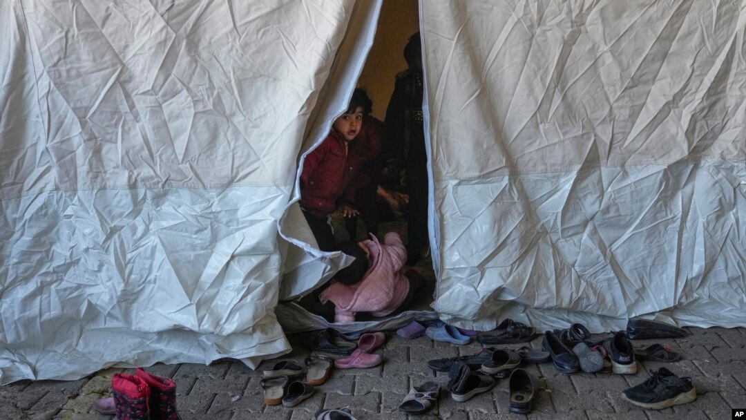 Un niño sirio mira desde el interior de una tienda de campaña utilizada como refugio en un mercado público en el distrito de Islahiye de Gaziantep, al sur de Turquía, el 11 de febrero de 2023.