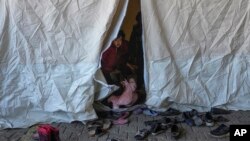 Un niño sirio mira desde el interior de una tienda de campaña utilizada como refugio en un mercado público en el distrito de Islahiye de Gaziantep, al sur de Turquía, el 11 de febrero de 2023.