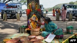 FILE - A former 'devadasi' woman places a flower garland on a decorated mask of the Hindu Goddess Yellamma Devi near a pond in Savadatti of Belgaum district, in India's Karnataka state, Sept. 21, 2022.