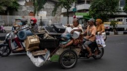 Becak berisi barang bekas yang akan dijual ke pasar loak di Surabaya, 1 Februari 2023. (Foto: JUNI KRISWANTO/AFP)