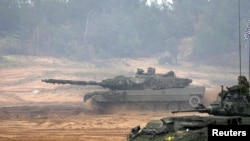 Tenk španske vojske Leopard 2 NATO pojačane borbene grupe Forward Presence prolazi pored oklopnog transportera kanadske vojske LAV tokom završne faze vojne vježbe Silver Arrow 2022 na vojnim poligonima Adazi, Latvija 29. septembra 2022. REUTERS/Ints Kalnins