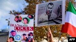 FILE - People hold portraits of Iranian rapper Toomaj Salehi, right, and children, left, who were killed during the protests in Iran, during a rally in Istanbul, on Nov. 26, 2022. 