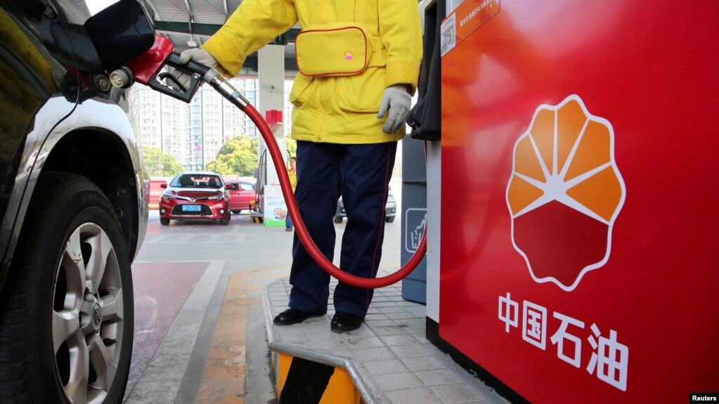 FILE - A gas station attendant pumps fuel into a customer's car at a PetroChina station in Nantong, Jiangsu province, China, March 28, 2018.