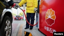 FILE - A gas station attendant pumps fuel into a customer's car at a PetroChina station in Nantong, Jiangsu province, China, March 28, 2018.