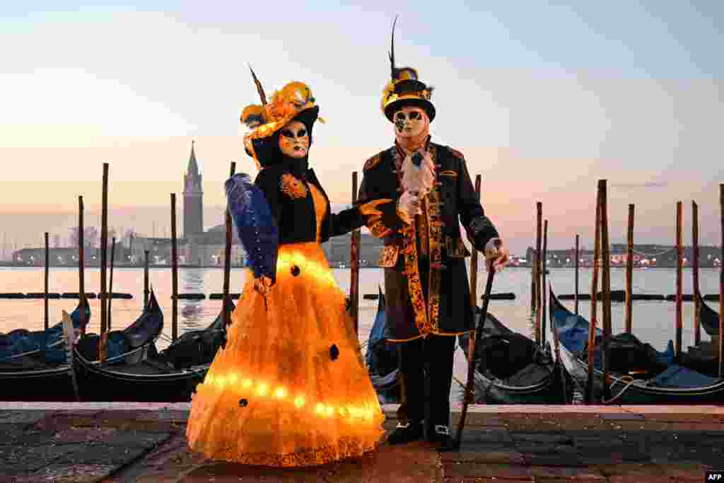Маскирани учесници облечени во традиционална карневалска носија позираат за време на карневалот во Венеција, Италија.