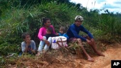 A family rest as they travel for days to leave the Yanomami Indigenous territory ahead of expected operations against illegal mining in Alto Alegre, Roraima state, Brazil, Feb. 7, 2023.