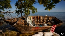 FILE - A wooden migrant boat lies grounded on the reef alongside mangroves, at Harry Harris Park in Tavernier, Fla., Jan. 19, 2023. 
