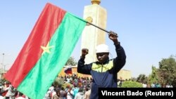 Un homme tient un drapeau national lors d'un rassemblement après le coup d'État qui a renversé le président Roch Kaboré, à Ouagadougou, au Burkina Faso, le 25 janvier 2022.