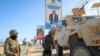 FILE - Ugandan peacekeepers with the African Transition Mission in Somalia (ATMIS) stand next to their armored vehicle in Mogadishu, Somala, May 10, 2022. 