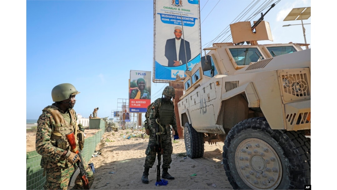 FILE - Ugandan peacekeepers with the African Transition Mission in Somalia (ATMIS) stand next to their armored vehicle in Mogadishu, Somala, May 10, 2022.