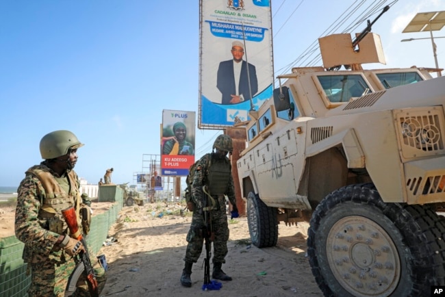 FILE - Ugandan peacekeepers with the African Transition Mission in Somalia (ATMIS) stand next to their armored vehicle in Mogadishu, Somala, May 10, 2022.